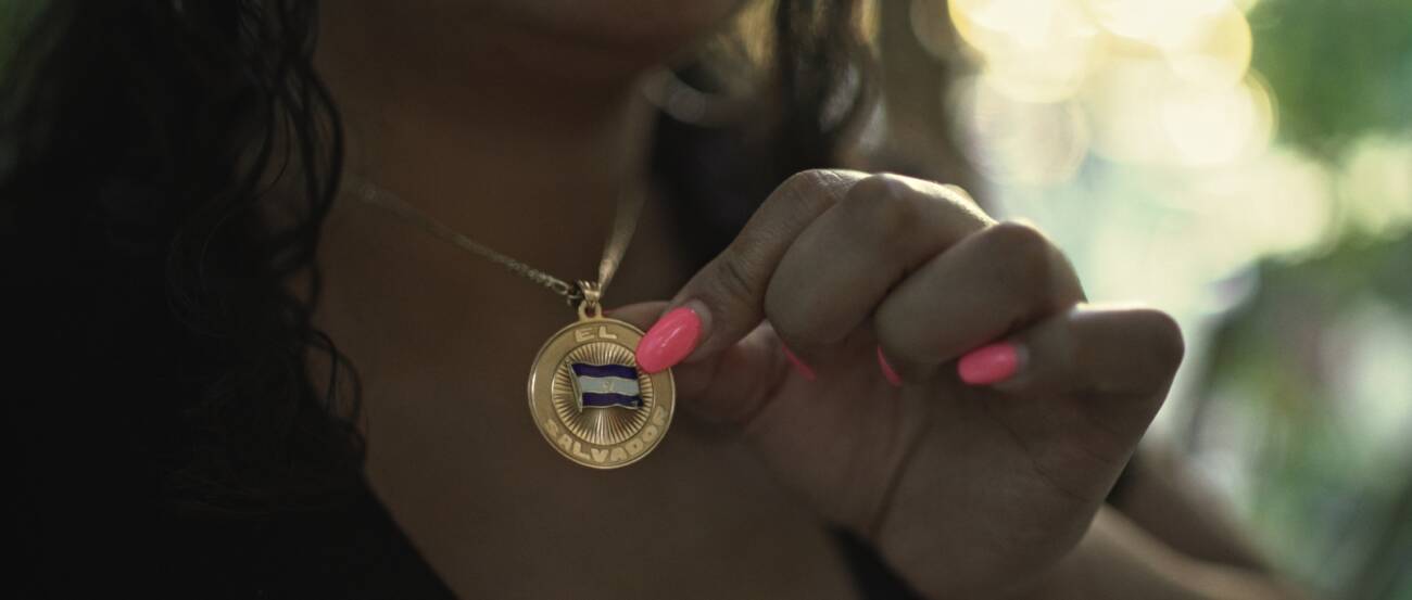 Mulher segurando medalha com a bandeira de El Salvador.