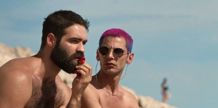 Dois homens conversando na praia em dia ensolarado.