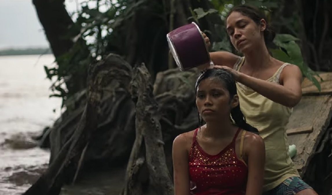 Mulher lavando cabelo de menina na floresta tropical.