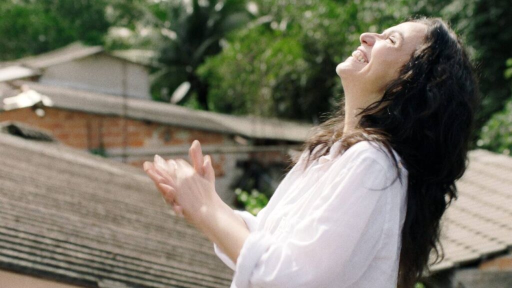 Mulher sorrindo, ao ar livre, dia ensolarado.