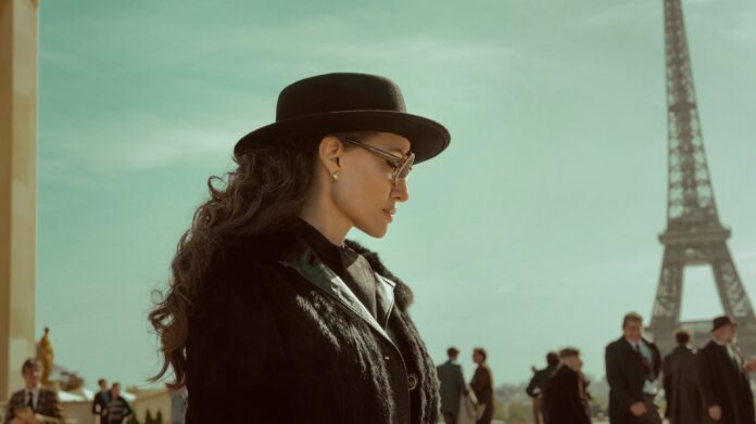 Mulher com chapéu em frente à Torre Eiffel.