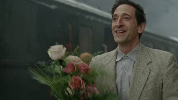 Homem sorrindo segurando buquê de flores na estação.