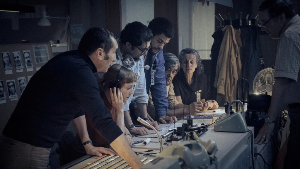 Pessoas reunidas ao redor de uma mesa de trabalho.