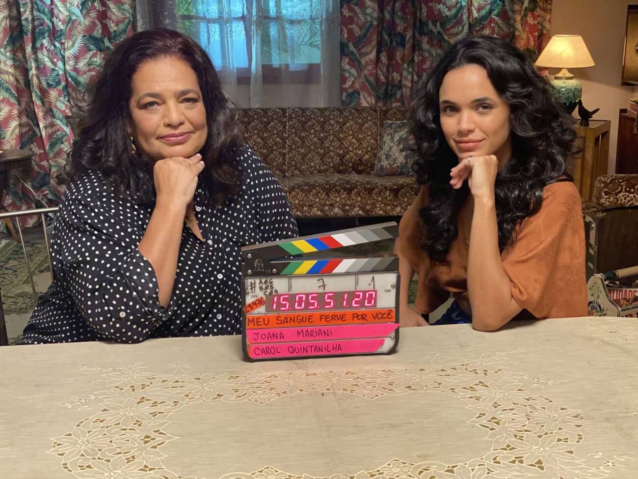 Duas atrizes em set de filmagem com claquete sobre mesa