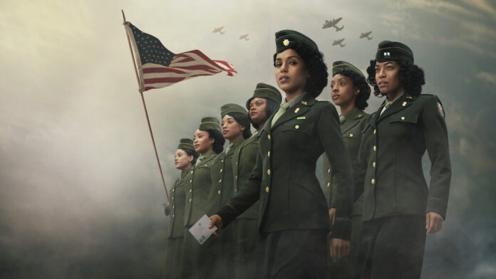 Mulheres militares com bandeira americana ao fundo.