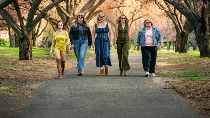 Mulheres estilosas caminhando em parque florido.